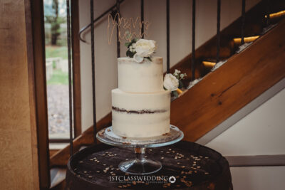 Elegant wedding cake with 'Mr & Mrs' topper on barrel.