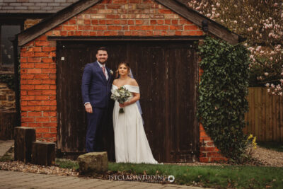 Bride and groom posing by rustic barn door.