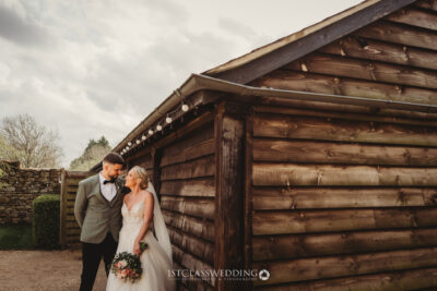 Bride and groom outside wooden cabin, rustic wedding theme.