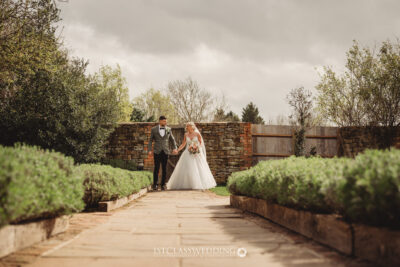 Bride and groom walking in garden pathway at Dodfrod Manor.