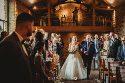 Bride walking down the aisle with father in rustic venue at Dodfrod Manor.