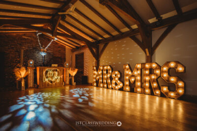 Rustic wedding venue with illuminated 'MR & MRS' sign.