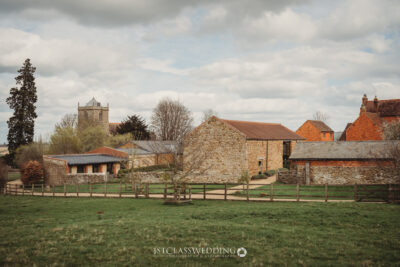 Rustic British countryside farm with church in background.