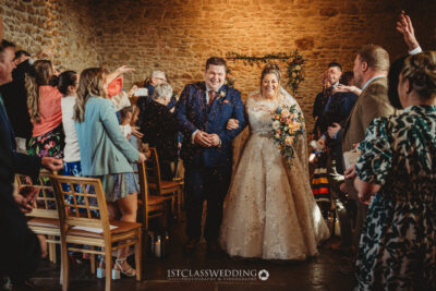 Bride and groom with confetti in rustic wedding venue.